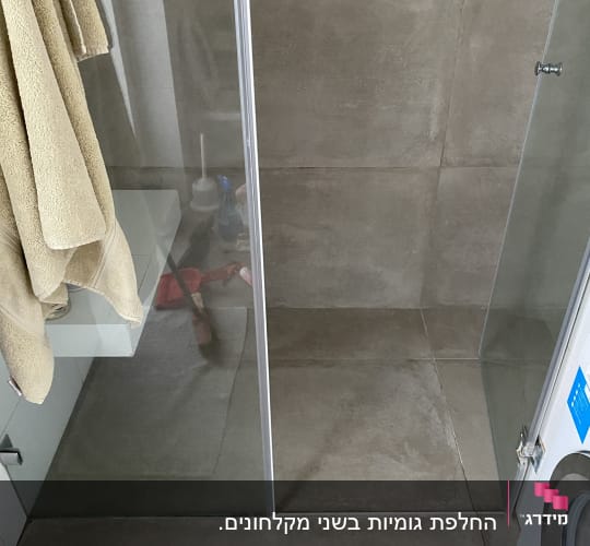 מקלחון זכוכית עם מגבות תלויים בצד